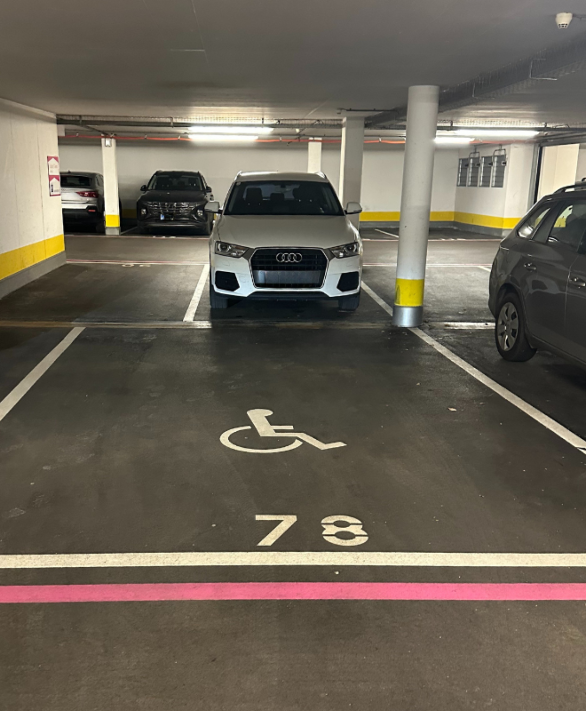 Ein freier Parkplatz mit Rollstuhlsymbol und ein Auto im Hintergrund