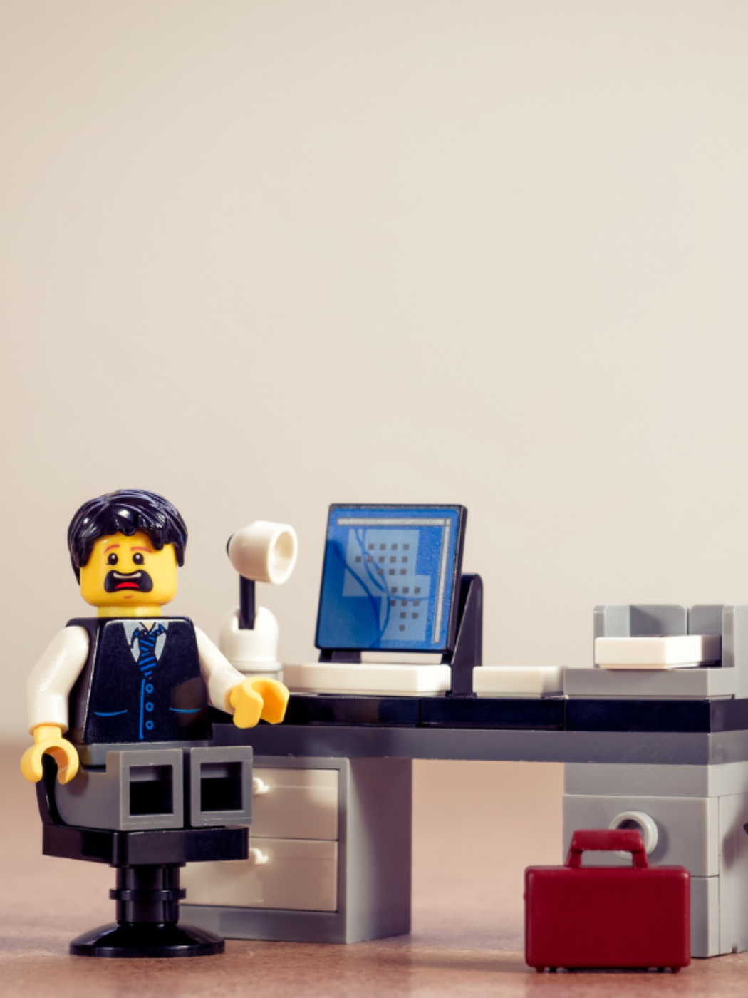 Die Lego Figur eines Beamten sitzt in einem Lego Büro mit entsetzen Gesichtsausdruck
