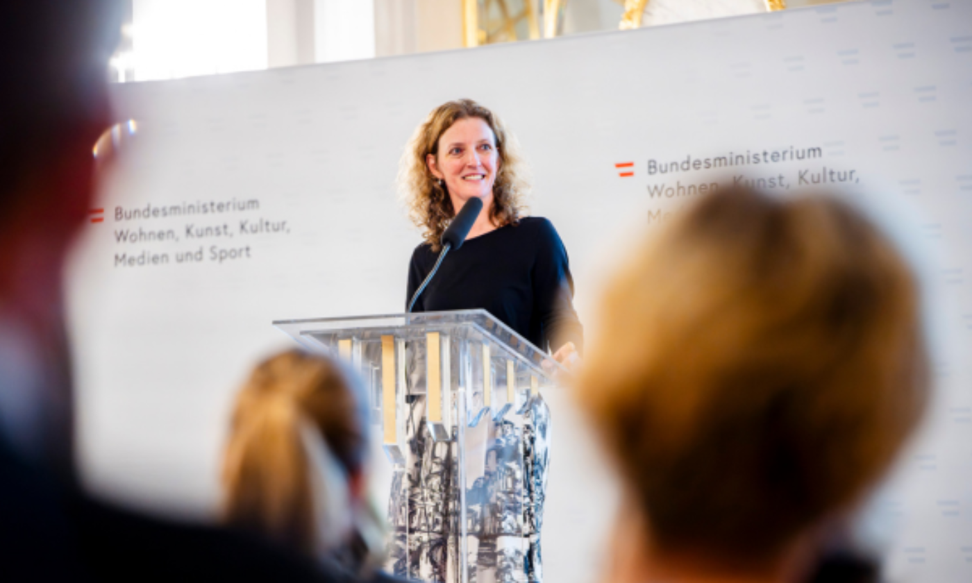 Abteilungsleiterin Petra Dietrich steht hinter einem Redepult mit Mikrofon.