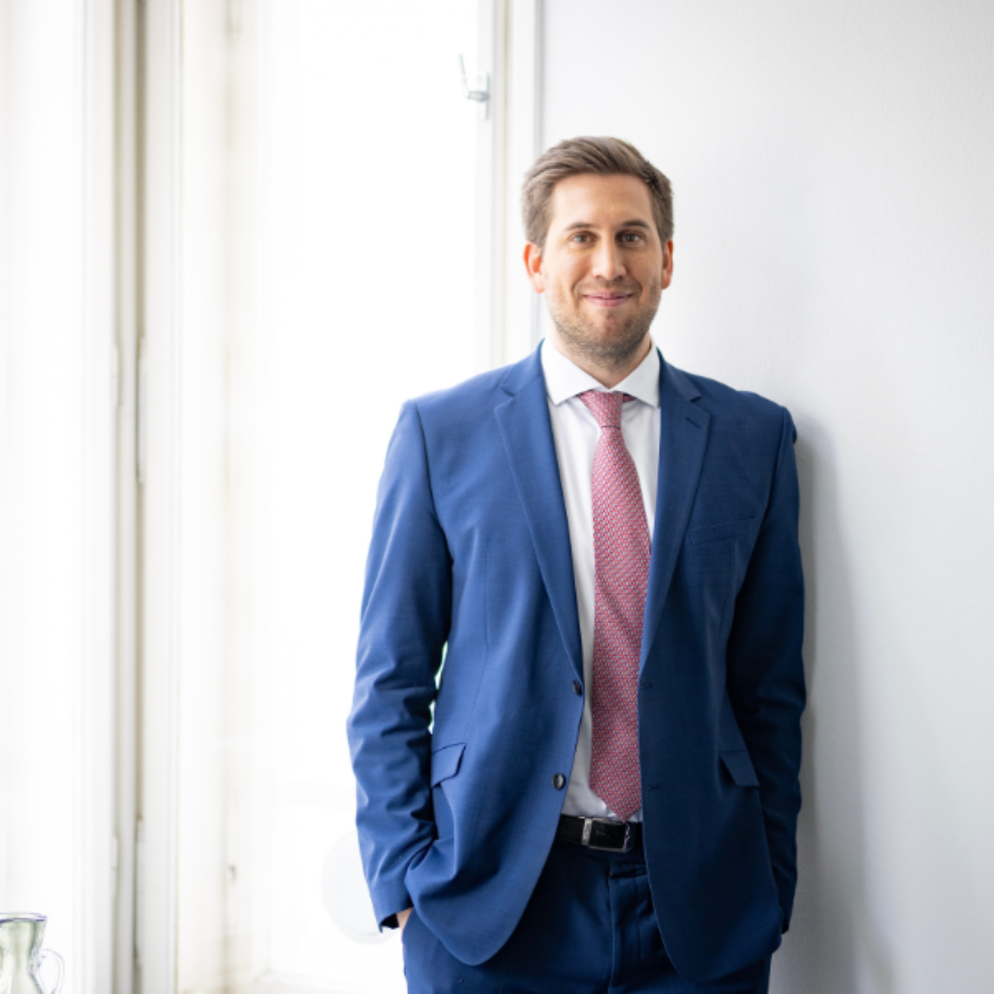 Staatssekretär Alexander Pröll lehnt an einer weißen Wand.